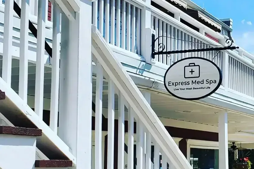 The Express Med Spa sign hanging from the porch of its building in Frankfort, Illinois, beside a white exterior staircase. Photo courtesy of expressmedspas.com.
