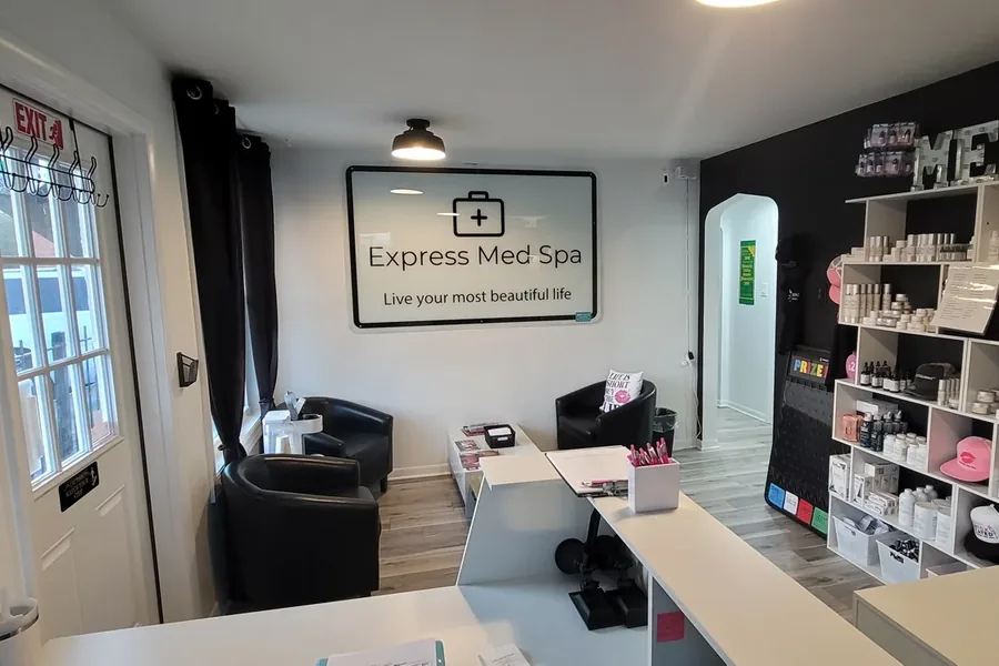 The front desk and waiting area inside Express Med Spa in Mount Greenwood, Chicago, with the Express Med Spa wall sign, black armchairs, and shelves of skincare products. Photo courtesy of expressmedspas.com.